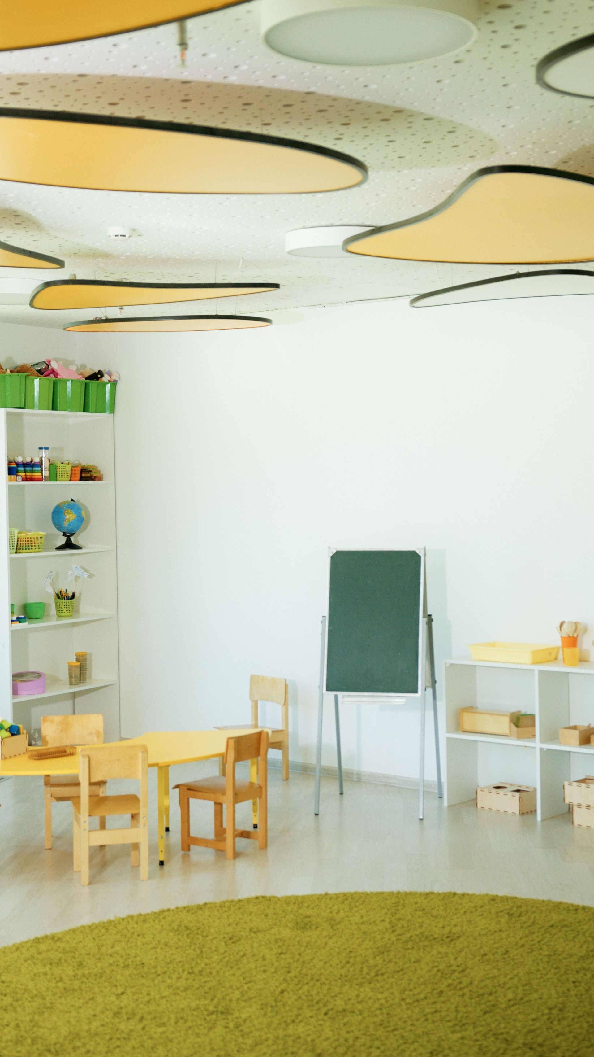 Bright, empty classroom with wooden furniture and creative ceiling design.