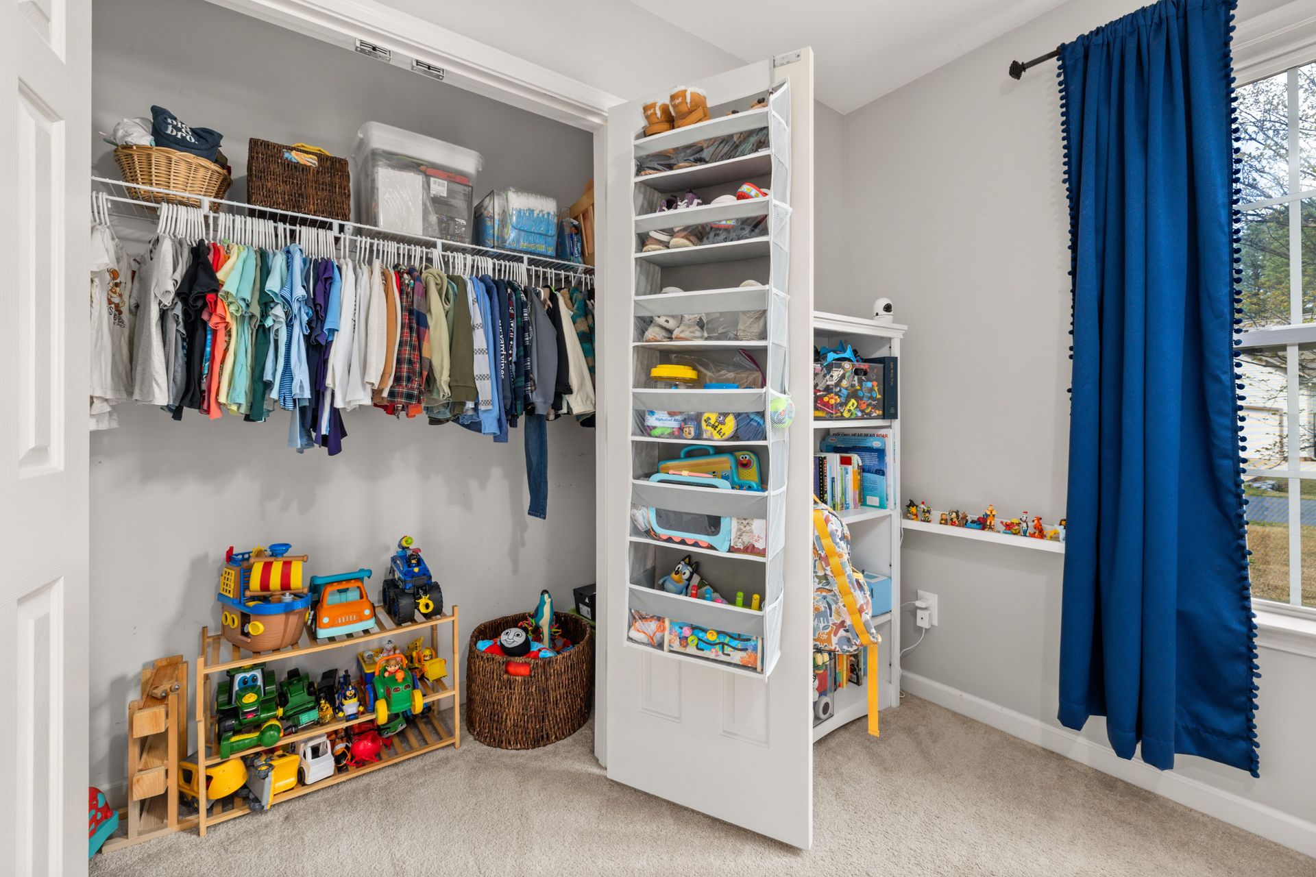 A neatly organized children's closet featuring clothes, toys, and storage solutions.