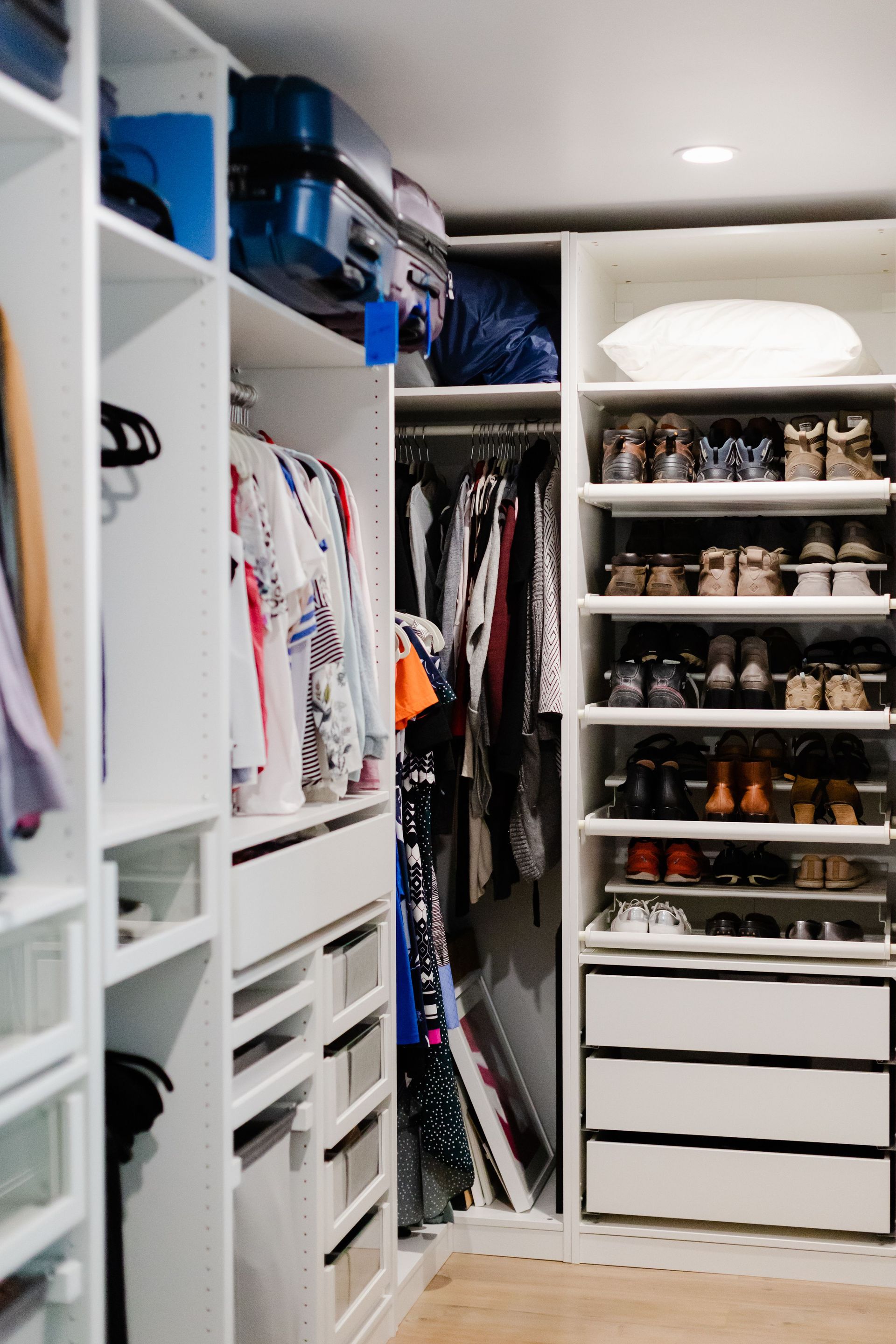 A well-organized walk-in closet featuring clothes and shoes neatly arranged on shelves.